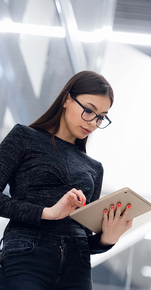 Woman wearing glasses looking at a tablet in her hands