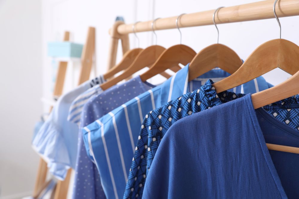 A clothing rack with several blue tops in different patterns.