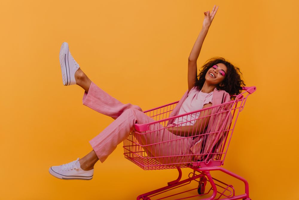 A woman sits in a pink shopping cart.